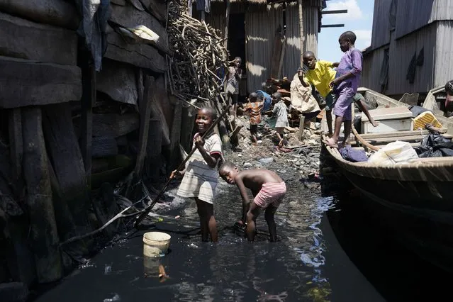 Children play in filthy water surrounded by garbage in Nigeria's economic capital Lagos' floating slum of Makoko, Monday, March. 20, 2023. March 22 is World Water Day, established by the United Nations and marked annually since 1993 to raise awareness about access to clean water and sanitation. (Photo by Sunday Alamba)/AP Photo