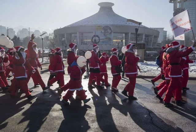 Revelers dressed as Father Frost, the equivalent of Santa Claus, walk past a building that holds circus performances during a parade in Almaty December 28, 2014. (Photo by Shamil Zhumatov/Reuters)