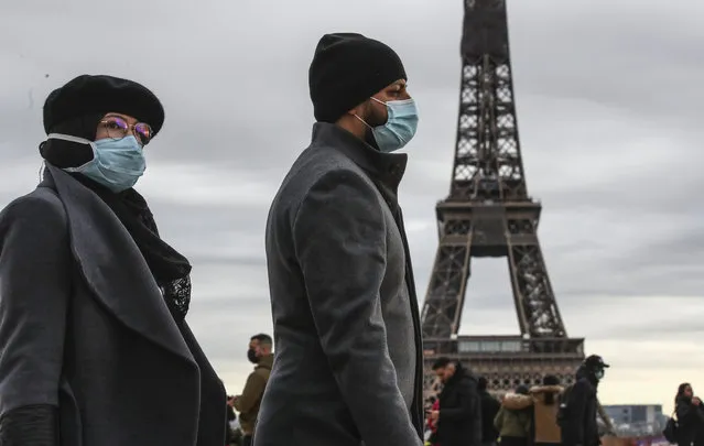 People wearing face makes to protect against the COVIS-19 walk at Trocadero plaza near Eiffel Tower in Paris, Saturday, December 26, 2020. French health authorities have confirmed the country's first case of the virus variant that prompted strict new lockdown measures in Britain and global travel restrictions. (Photo by Michel Euler/AP Photo)