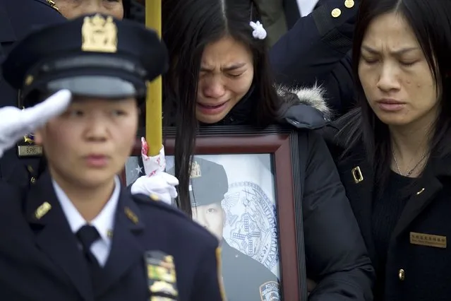 Widow Pei Xia Chen reacts while clutching a photo of slain New York Police Department officer Wenjian Liu as his casket departs his funeral in the Brooklyn borough of New York January 4, 2015. New York Mayor Bill de Blasio appealed for reconciliation on Sunday in his eulogy for the second of two police officers murdered last month, two deaths that led to accusations the mayor had contributed to an anti-police climate. (Photo by Carlo Allegri/Reuters)