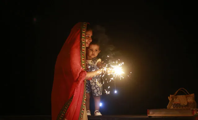 A Hindu woman lights a firecrackers with her daughter to celebrate Diwali, the Hindu festival of lights, in Mumbai, India, Sunday, October 30, 2016. Hindus across the country are celebrating Diwali, dedicated to the goddess of wealth Lakshmi. (Photo by Rafiq Maqbool/AP Photo)