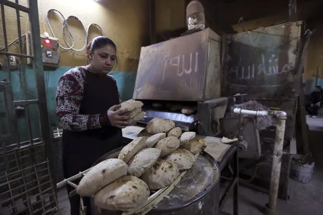 A female worker takes bread out of an oven at a bakery in Cairo, January 8, 2015. (Photo by Mohamed Abd El Ghany/Reuters)