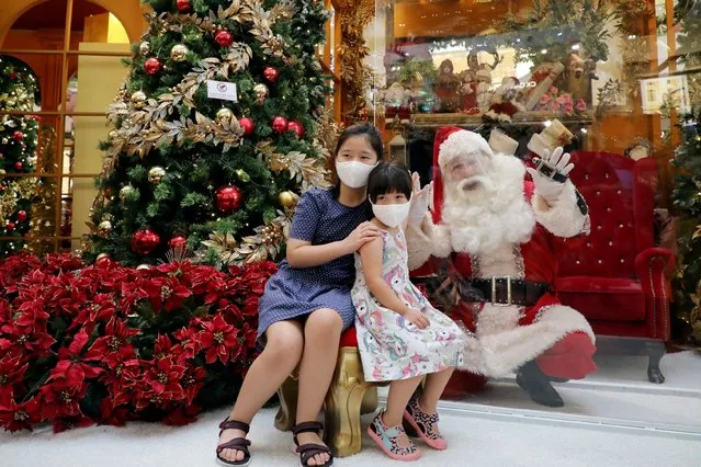 A man dressed as Santa Claus poses for a picture behind a protective shield with girls wearing masks in a shopping mall amid the coronavirus disease (COVID-19) outbreak in Kuala Lumpur, Malaysia on December 9, 2020. (Photo by Lim Huey Teng/Reuters)