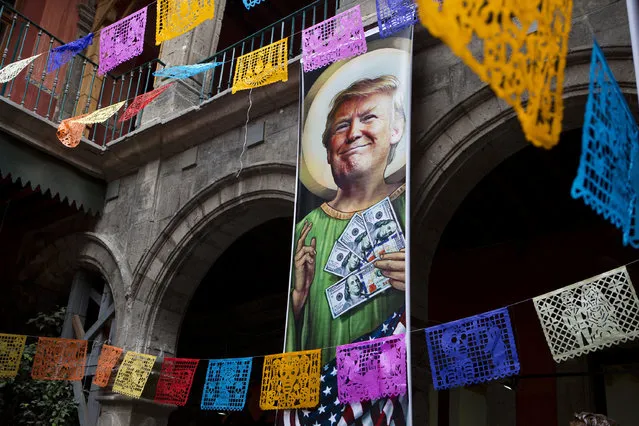 A banner with an image of Donald Trump promotes an exhibition titled; “Trump: A wall of caricatures”, surrounded by papel picado, or intricately-cut tissue paper, with Day of the Dead designs, inside the Caricature Museum in downtown Mexico City, Thursday, November 10, 2016. The exhibition, which features dozens of works by Mexican and international cartoonists, mocks amongst other things the president-elect's derogatory statements about Mexicans and his plans to build a wall between the two countries. (Photo by Rebecca Blackwell/AP Photo)
