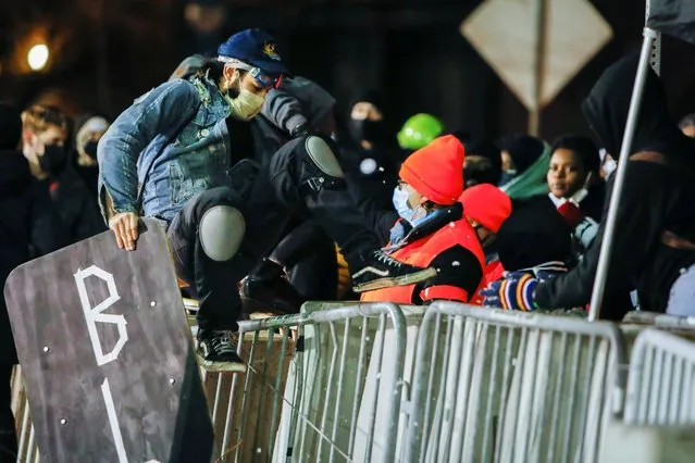 Protestors jump over barricades at the Public Safety Building after the New York grand jury voted not to indict police officers in Daniel Prude's death in Rochester, New York, U.S., February 23, 2021. (Photo by Lindsay DeDario/Reuters)