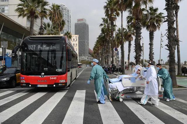 Medical personnel of Hospital del Mar take COVID-19 patient, Marta Pascual, 72, back to the hospital after getting some fresh air by the sea, at the Barceloneta beach esplanade in Barcelona on March 4, 2021. (Photo by Lluis Gene/AFP Photo)