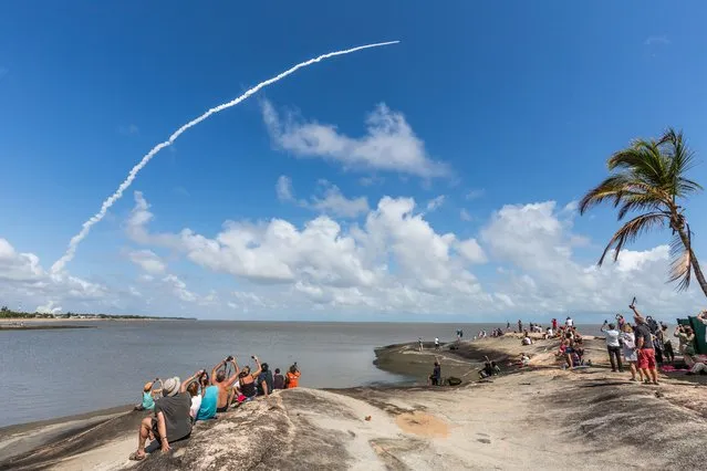 People take photos as an Ariane 5 space rocket with a payload of four Galileo satellites lifts off from ESA's European Spaceport in Kourou, French Guiana, on November 17, 2016. Ariane 5 successfully launched on November 17 four satellites which will be part of the Galileo global satellite navigation system. (Photo by Jody Amiet/AFP Photo)