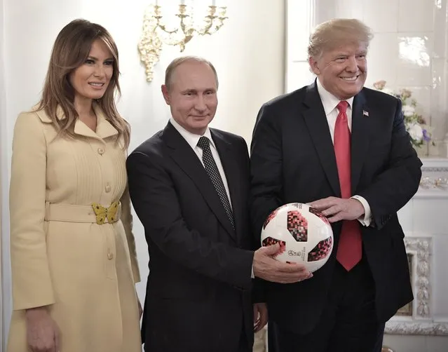 U.S. First Lady Melania Trump, left, Russian President Vladimir Putin, center, and U.S. President Donald Trump, pose with a soccer ball after a press conference following their meeting at the Presidential Palace in Helsinki, Finland, Monday, July 16, 2018. (Photo by Alexei Nikolsky, Sputnik, Kremlin Pool Photo via AP Photo)