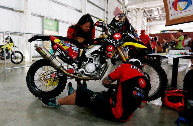 Daniel Gouet (bottom) of Chile works on his Susuki motorcycle at the technical verification area ahead of the Dakar Rally 2016 in Buenos Aires, Argentina, January 1, 2016. (Photo by Marcos Brindicci/Reuters)