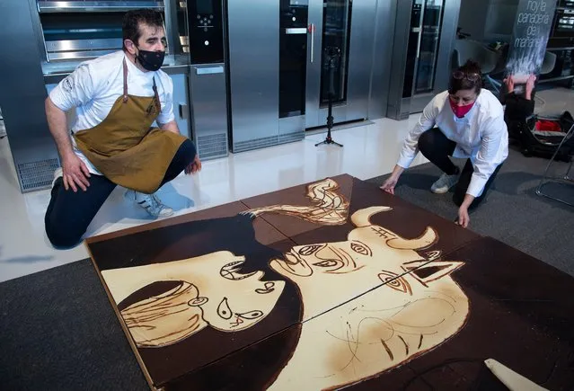 Members of Euskal Gozogileak (Basque Confectioners) association work on a life-size chocolate version of Picasso's painting “Guernica” in the Spanish Basque town of Lezo on April 16, 2021. The 7.70 x 3.50 meter chocolate replica of “Guernica” will be exhibited from April 25 onward in the town of Gernika to commemorate the 85th anniversary of the bombing raid of the small Basque town by Nazi aircraft, at the behest of General Francisco Franco in 1937. (Photo by Ander Gillenea/AFP Photo)