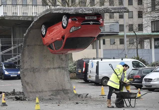 A man works near an upside down car art installation in a car park on the South Bank in London, February 19, 2015. (Photo by Toby Melville/Reuters)