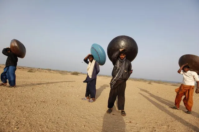 Men carry floating pitchers which they use to catch fish while heading home in Soneri village next to Keenjhar Lake, near Thatta, February 22, 2015. (Photo by Akhtar Soomro/Reuters)