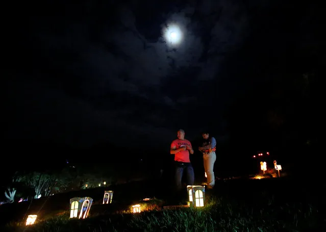 People light candles, next to a grave in the cemetery “Jardines de la Aurora”, to mark the beginning of the Christmas festivities, in Cali, Colombia, December 7, 2016. (Photo by Jaime Saldarriaga/Reuters)