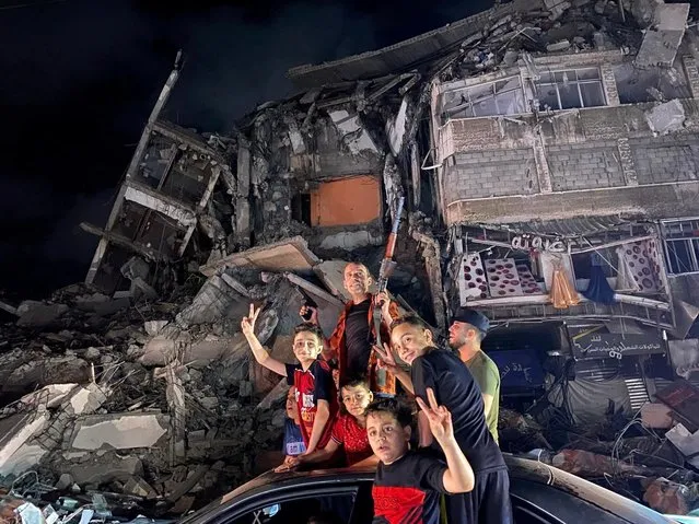 People gesture near the rubble of a damaged building as Palestinians celebrate in the streets following a ceasefire, in Gaza City on May 21, 2021. (Photo by Mohammed Salem/Reuters)