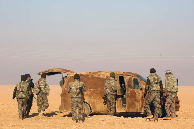 Fighters from the Kurdish-Arab alliance, known as the Syrian Democratic Forces, gather next to a vehicle covered with mud in a field near the Syrian town of al-Naseem, located some 50 kilometres on the western outskirts of the Islamic State (IS) bastion of Raqa, on December 12, 2016. The US-backed alliance announced on December 10, 2016 it would launch the second phase of its battle for the IS group's de facto Syrian capital of Raqa. (Photo by Delil Souleiman/AFP Photo)