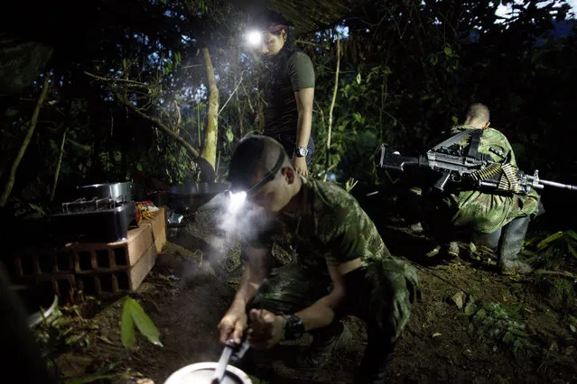 In this January 3, 2016 photo, with the aid of head lamps, rebel fighters for the 36th Front of the Revolutionary Armed Forces of Colombia or FARC, prepare a breakfast of rice, beans, sausages and coffee, in their hidden camp in Antioquia state, in the northwest Andes of Colombia. The day begins around 4:30 a.m. inside the temporary camp, home to 22 rank and file fighters, 4 commanders and 2 dogs. All rank and file are expected to share in kitchen patrol. (Photo by Rodrigo Abd/AP Photo)