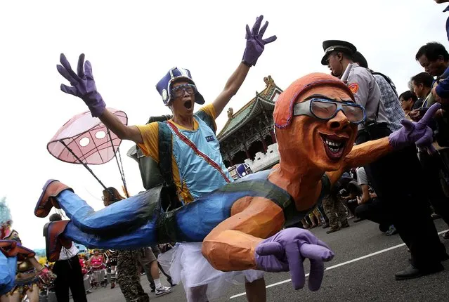 A man wearing a papier-mache figure shows his spirit as he marches during the “Dream Parade” in Taipei, Taiwan, on Oktober 19, 2013. (Photo by Chiang Ying-ying/Associated Press)