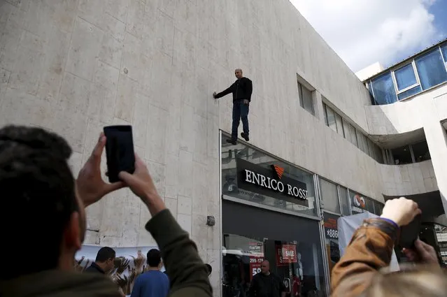 Onlookers take pictures of a purported levitation trick by Israeli illusionist and endurance artist Hezi Dean (top) in Tel Aviv March 22, 2015. (Photo by Baz Ratner/Reuters)