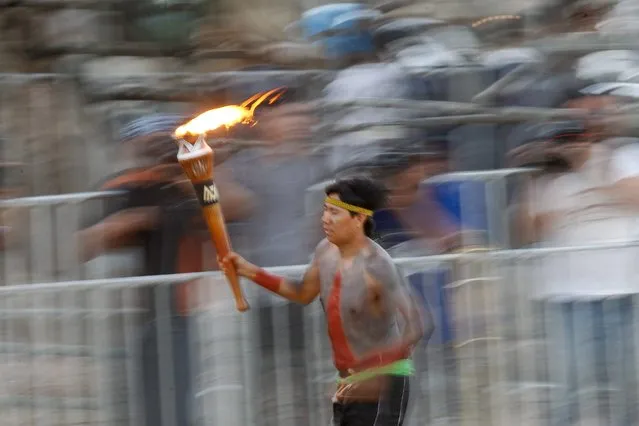 A Brazilian indigenous runs with the torch during opening ceremony of XII Brazilian Indigenous Games in Cuiaba, Brazil, 09 November 2013. 1600 indigenous from 48 Brazilian ethnic groups will compete in ten traditional disciplines. (Photo by Fernando Bizerra Jr./EPA)
