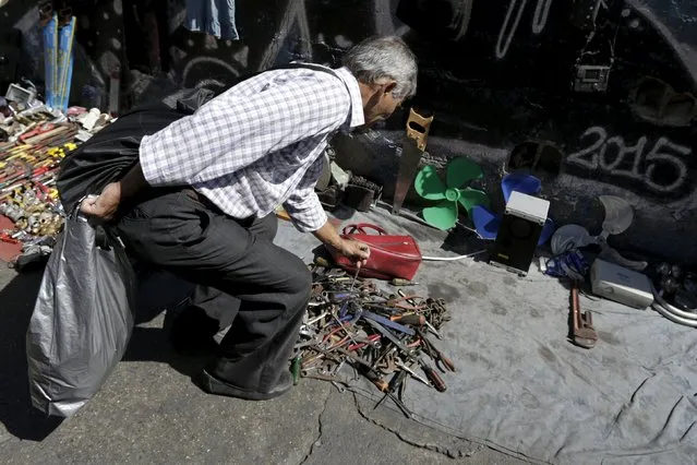 A man chooses used items for sale at an improvised store at a main street in Caracas, January 25, 2016. (Photo by Marco Bello/Reuters)