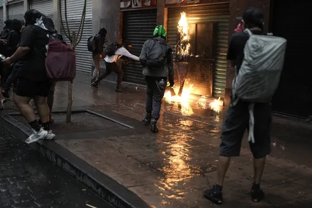 Demonstrators attempt to torch a store after a march to mark the 55th anniversary of the killings of student protesters at Tlatelolco plaza when soldiers opened fire on a peaceful demonstration, in Mexico City, Monday, October 2. 2023. (Photo by Eduardo Verdugo/AP Photo)