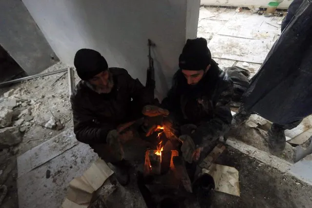 Rebel fighters warm themselves around a fire as they rest at al-Breij frontline, after what they said an advance by them in the area and they took control of 2 factories and several buildings where forces loyal to Syria's President Bashar al-Assad were stationed, in Aleppo January 5, 2015. (Photo by Hosam Katan/Reuters)