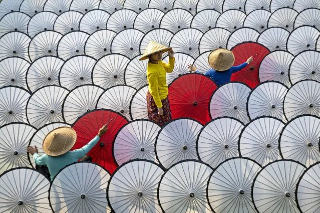 Three workers prepare to paint some traditional umbrellas in Bogor, Indonesia in the second decade of October 2023. The daily wage is the equivalent of the cost of selling one umbrella to a tourist. (Photo by Achmad Mikami/Solent News)
