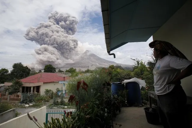 A villager watches as Mount Sinabung releases pyroclastic flows seen from Tiga Serangkai, North Sumatra, Indonesia, Wednesday, April 1, 2015. Mount Sinabung, among about 130 active volcanoes in Indonesia, has sporadically erupted since 2010 after being dormant for more then 400 years. (Photo by Binsar Bakkara/AP Photo)