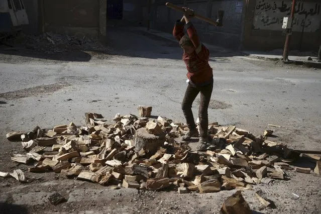 A boy cuts firewood along a street in the Douma neighbourhood of Damascus, Syria February 9, 2016. (Photo by Bassam Khabieh/Reuters)