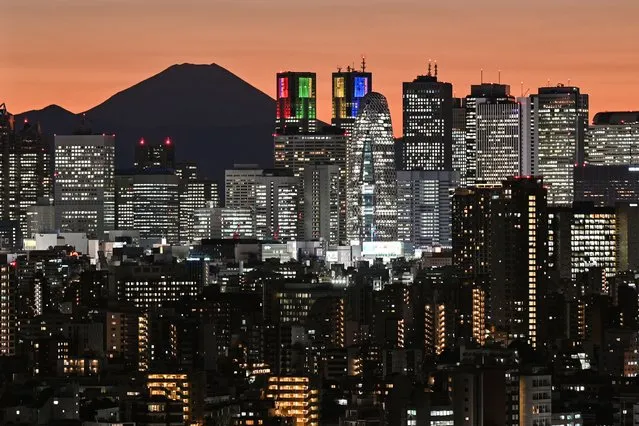 Mount Fuji (back L), Japan's highest mountain at 3,776 meters (12,389 feet), is silhouetted during sunset behind the highrise buildings of the Shinjuku area in downtown Tokyo on November 20, 2023. (Photo by Richard A. Brooks/AFP Photo)