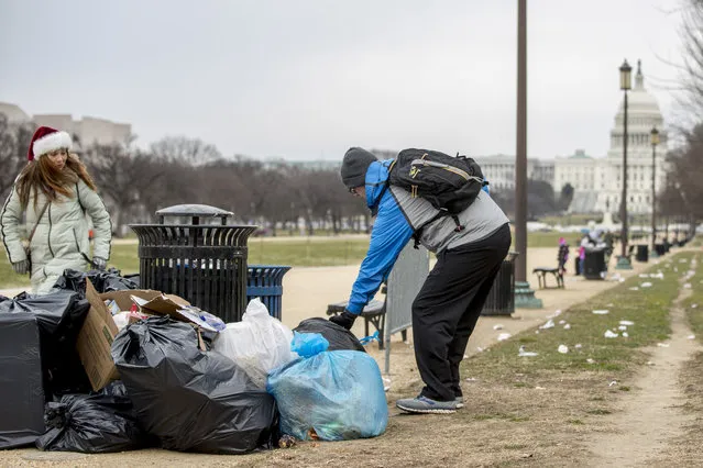 The Capitol building is visible as a man who declined to give his name picks up garbage and stacks it near a trash can during a partial government shutdown on the National Mall in Washington, Tuesday, December 25, 2018. (Photo by Andrew Harnik/AP Photo)