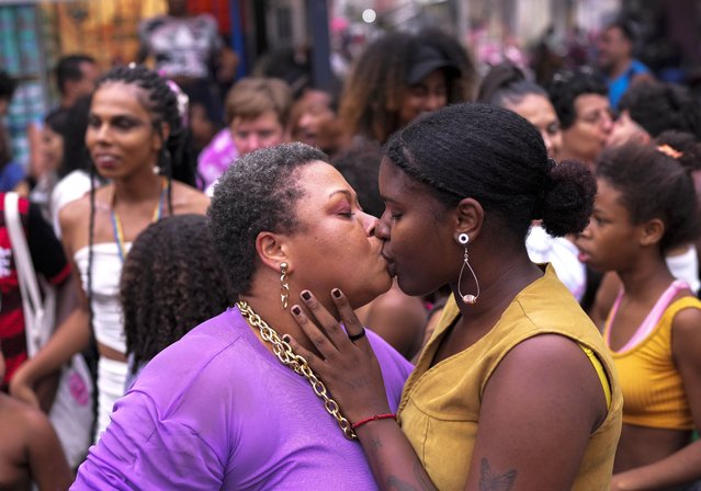 A couple kiss during the Gay Pride Parade at the Mare slum in Rio de Janeiro, Brazil, Sunday, November 26, 2023. (Photo by Silvia Izquierdo/AP Photo)