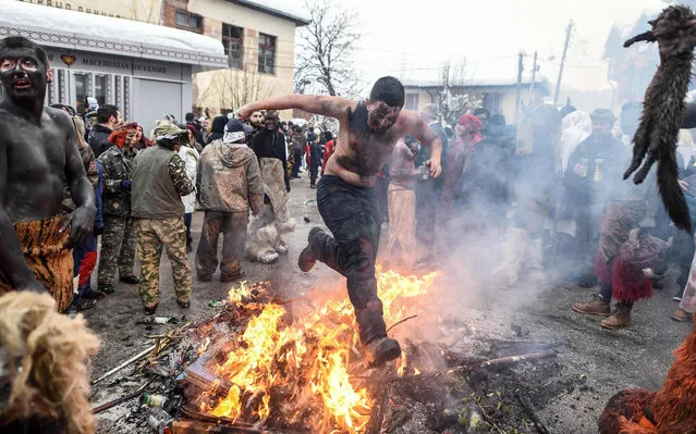 A reveler jumps over an open fire during the traditional mask burning on the second day of a carnival procession through the village of Vevcani, on January 14, 2019. The Vevcani Carnival is said to be 1.400 years old and is held every year on the eve of the feast of Saint Basil (January 14), which also marks the beginning of the New Year according to the Julian calendar, observed by the Macedonian Orthodox Church. (Photo by Robert Atanasovski/AFP Photo)