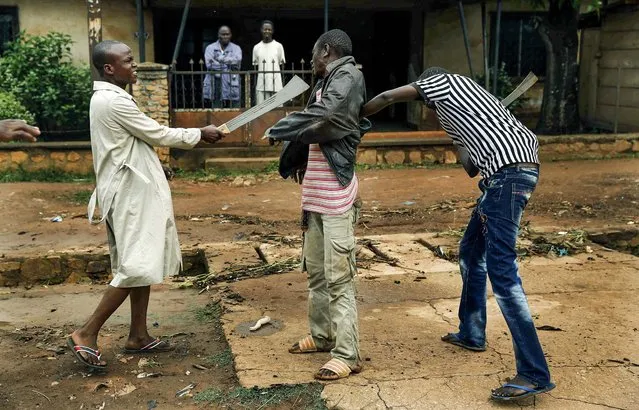 Muslim men organized in militias with machetes rough up a Christian man while checking him for weapons in Bangui, Central African Republic, on December 13, 2013. A band of about a dozen Muslim men with machetes faced off against an equally large group of Christian youths. (Photo by Jerome Delay/Associated Press)