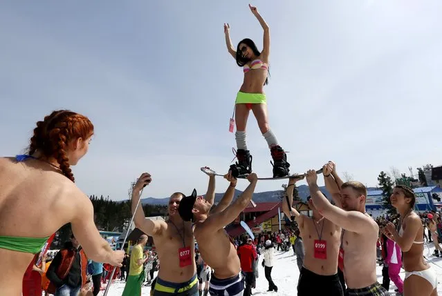 Men hold a woman on a snowboard as they pose for a picture after finishing a “downhill ski and snowboard descent in swimwear” event on Mount Zelyonaya (The Green Mount), at a ski resort near the town of Sheregesh in the Siberian Kemerovo region April 18, 2015. (Photo by Ilya Naymushin/Reuters)