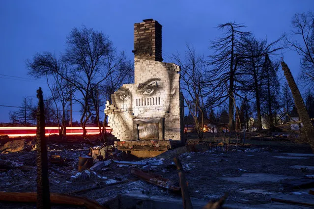 In this February 8, 2019, photo, a mural by artist Shane Grammer adorns the chimney of a residence leveled by the Camp Fire in Paradise, Calif. Grammer says he painted murals throughout the fire-ravaged town to convey hope in the midst of destruction. In the 100 days since a wildfire nearly burned the town of Paradise off the map, the long recovery is just starting. Work crews have been cutting down trees and clearing burned-out lots, but Paradise is mostly a ghost town where survivors still dig for keepsakes in the foundations of their homes. (Photo by Noah Berger/AP Photo)