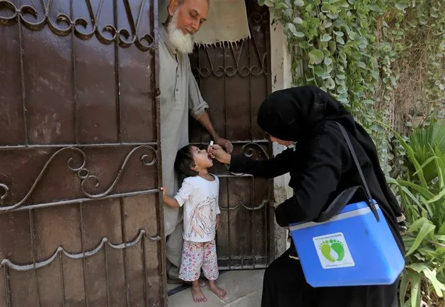 A health worker administers a polio vaccine to a child at a neighborhood of Karachi, Pakistan, Monday, September 20, 2021. The government launched polio vaccination drives across Pakistan in hopes to eradicate the crippling disease by the end of the year. (Photo by Fareed Khan/AP Photo)