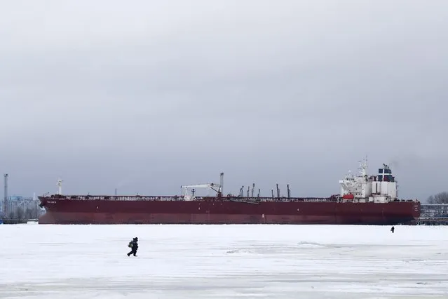 Fishermen walk while ice fishing on the Gulf of Finland in front of the crude oil tanker Sea Luck III, in St. Petersburg, Russia, 24 January 2024. The temperatures in St. Petersburg have reached four degrees Celsius. (Photo by Anatoly Maltsev/EPA/EFE)