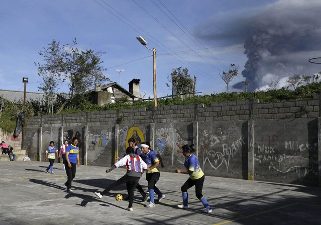 Women play soccer as  the Tungurahua volcano spews a column of ash during an eruption in Huambalo, Ecuador, Saturday, March 5, 2016. Tungurahua is 16,480 feet (5,023 meters) high and has been active since 1999. (Photo by Dolores Ochoa/AP Photo)