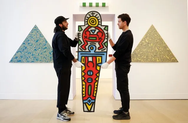 Phillips auction house staff members carry an artwork by Keith Haring titled “Totem” (1988) during the Philips Editions exhibition in London, Britain, 11 January 2024. The artwork is expected to fetch between 150,000 - 200,000 euros at auction 17-18 January. (Photo by Andy Rain/EPA)