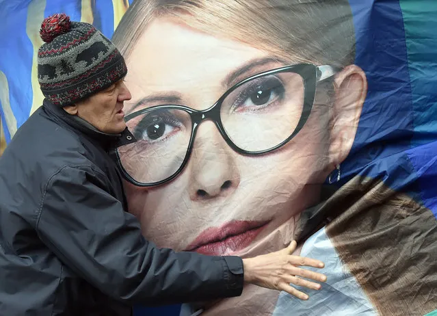 A supporter tries to stabilise a campaign booth of former Ukrainian Prime Minister and presidential candidate Yulia Tymoshenko during heavy wind in central Kiev, on March 26, 2019, ahead of Ukraine's presidential elections on March 31. (Photo by Sergei Supinsky/AFP Photo)