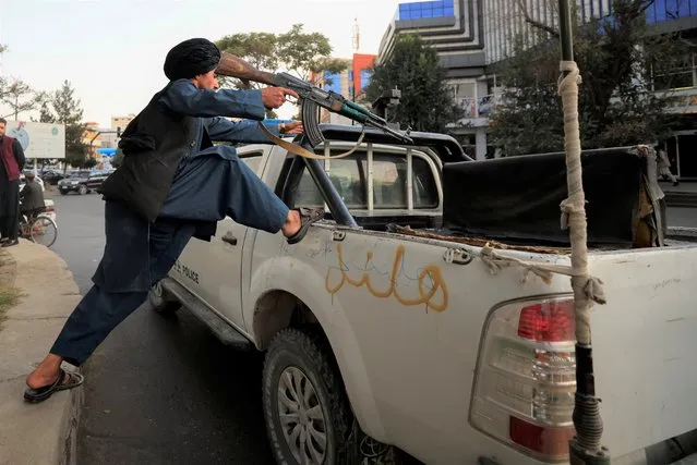 A Taliban fighter jumps into the vehicle after praying at Deh Bori square in Kabul, Afghanistan on October 18, 2021. (Photo by Zohra Bensemra/Reuters)