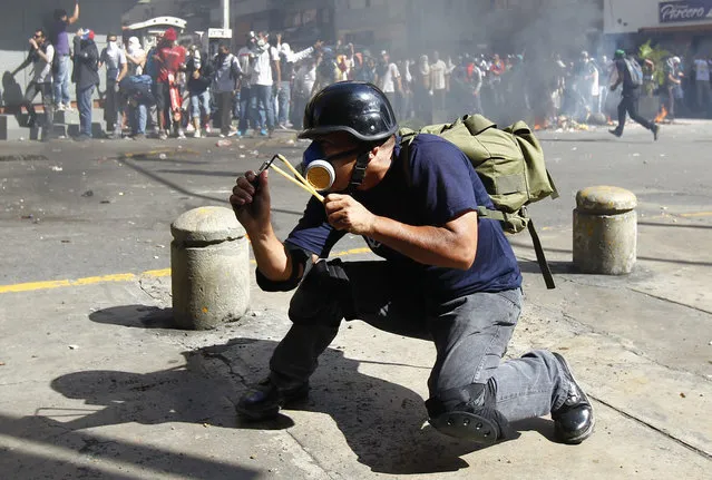 An opposition demonstrator aims a slingshot at police during a protest against Venezuela's President Nicolas Maduro's government in Caracas February 12, 2014. A demonstrator (not pictured) was killed during the anti-government rally in Caracas on Wednesday, Reuters witnesses said. (Photo by Carlos Garcia Rawlins/Reuters)