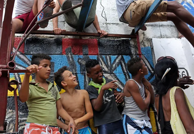 Cuban children listen to a group of Afro-Cuban musicians performing in an alleyway in downtown Havana, Cuba, Sunday, March 20, 2016, before the arrival of President Barack Obama. In his historic visit to Cuba, Obama is relegating decades of American acrimony with the communist country further into the past and cementing a new relationship between the Cold War-era foes. (Photo by Enric Marti/AP Photo)