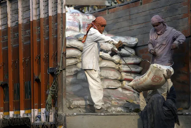 Workers unload cement bags from a truck near the construction site of residential buildings in New Delhi, India, March 10, 2016. (Photo by Anindito Mukherjee/Reuters)