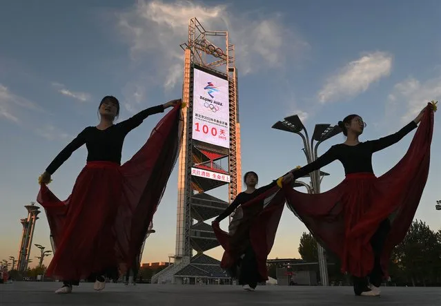 Dancers perform in front of the countdown clock showing 100 days until the opening of the 2022 Beijing Winter Olympics, at the Olympic Park in Beijing on October 27, 2021. (Photo by Noel Celis/AFP Photo)
