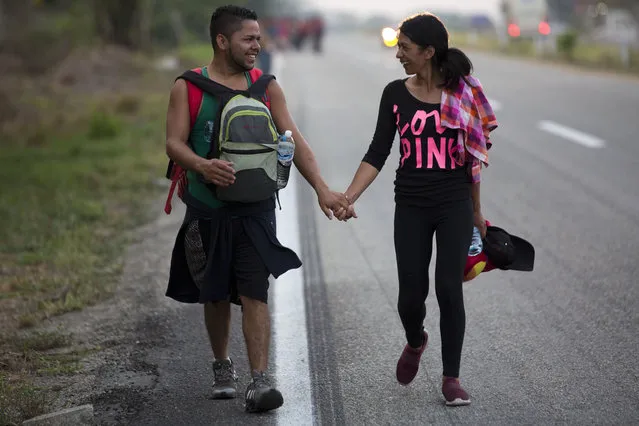 Central American migrants traveling in a caravan to the U.S. border walk hand in hand on the shoulder of a road in Pijijiapan, Mexico, Monday, April 22, 2019. The outpouring of aid that once greeted Central American migrants as they trekked in caravans through southern Mexico has been drying up, so this group is hungrier, advancing slowly or not at all, and hounded by unhelpful local officials. (Photo by Moises Castillo/AP Photo)