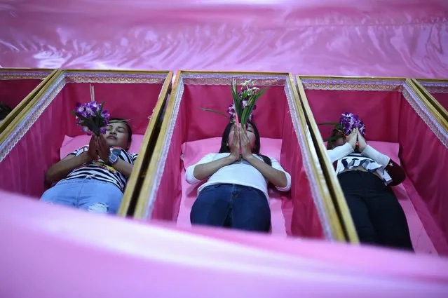 Devotees offering prayers as they lie in coffins during a group resurrection ceremony at the Wat Ta Kien Buddhist temple on January 16, 2016 in Nonthaburi on the outskirts of Bangkok. Ever since monks first began performing this ritual in 2008, dozens of people have been coming each day to Wat Ta Kien temple, undergoing a symbolic death as they're looking for the chance to start again. (Photo by Christophe Archambault/Getty Images)