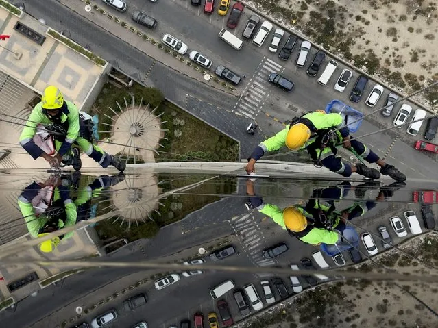 Window-cleaners known as “Spidermen” clean windows of a sky-scrapper during early hours in Manama, Bahrain, on March 16, 2024. (Photo by Hamad I Mohammed/Reuters)