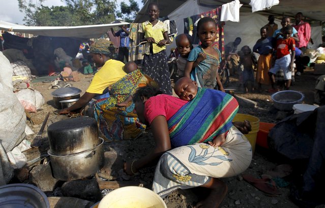 A Burundian refugee prepares food near their makeshift shelters as they gather on the shores of Lake Tanganyika in Kagunga village in Kigoma region in western Tanzania, to wait for MV Liemba to transport them to Kigoma township, May 17, 2015. (Photo by Thomas Mukoya/Reuters)